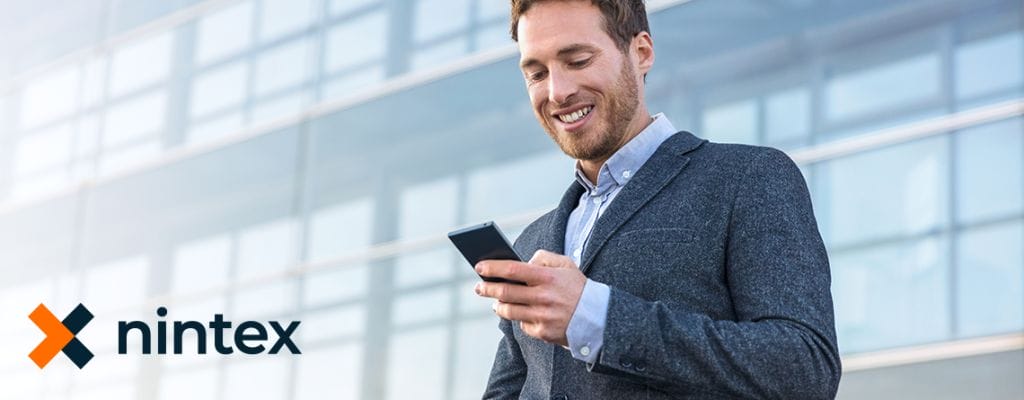 Ein Mann im Anzug hält ein Nintex Mobile-fähiges Mobiltelefon vor ein Gebäude und erkundet alle Möglichkeiten, die es bietet.