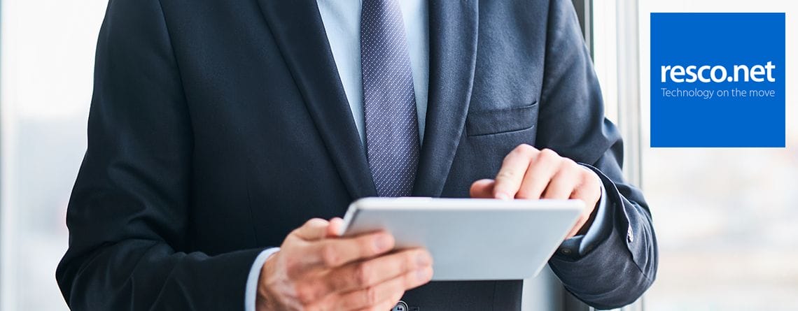 Ein Mann im Anzug hält eine Resco Mobile App auf einem Tablet, die Effizienz im Außendienst und Produktivitätsnachrichten präsentiert.